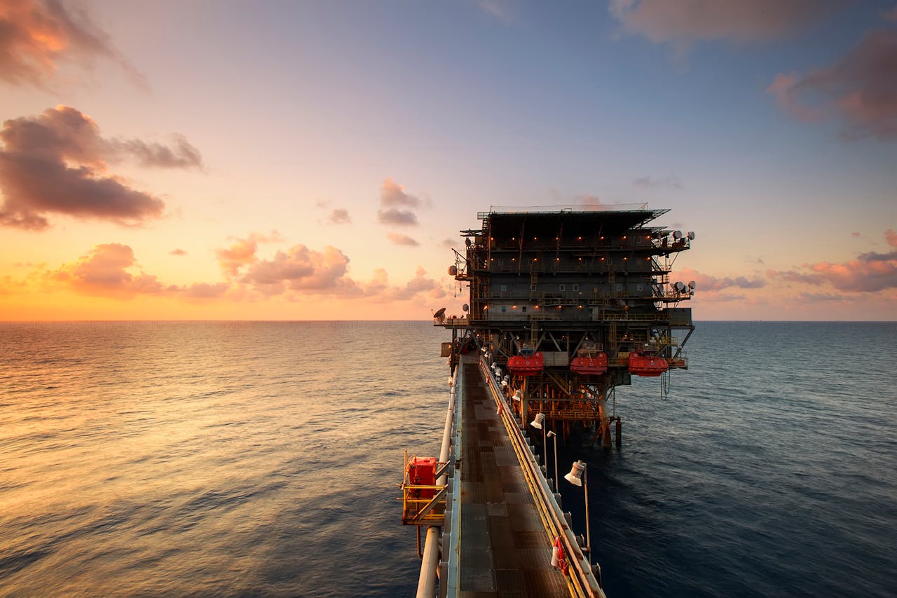 about-us A breathtaking view of an oil platform on the ocean at sunset, showcasing industrial beauty.